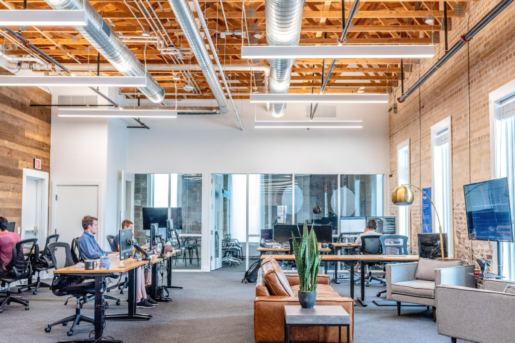 Open-concept office space with modern furniture and employees working at desks.