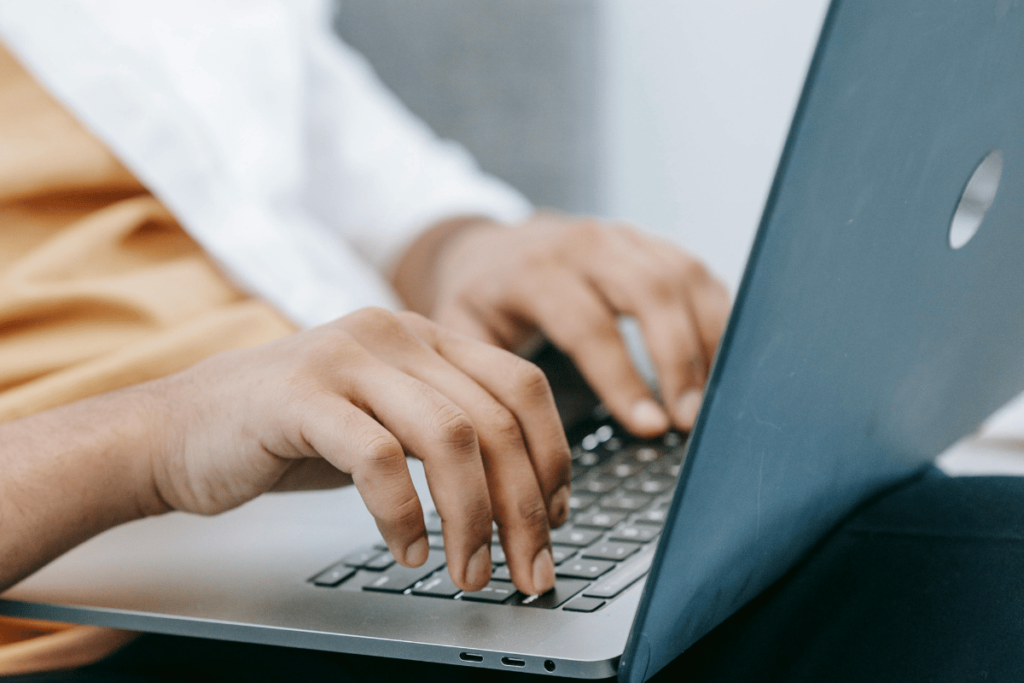 Close-up of hands typing on a silver laptop keyboard.
