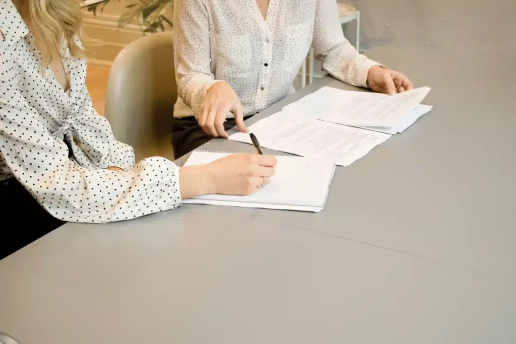 Close-up of two businesswomen reviewing and discussing documents at a table.