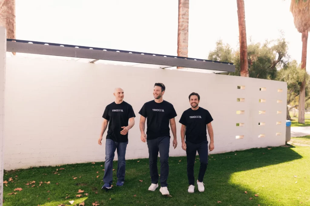 Team camaraderie shown as three men in matching 'TRIOSEO' shirts walk together.