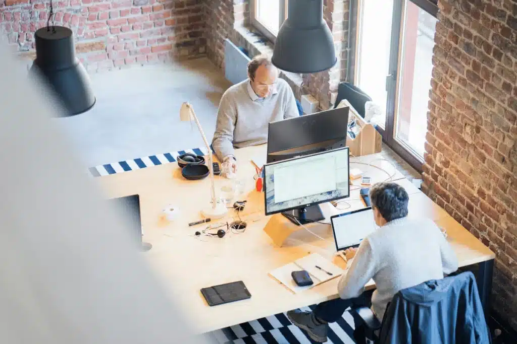Bright office space with two men focused on their computer screens.