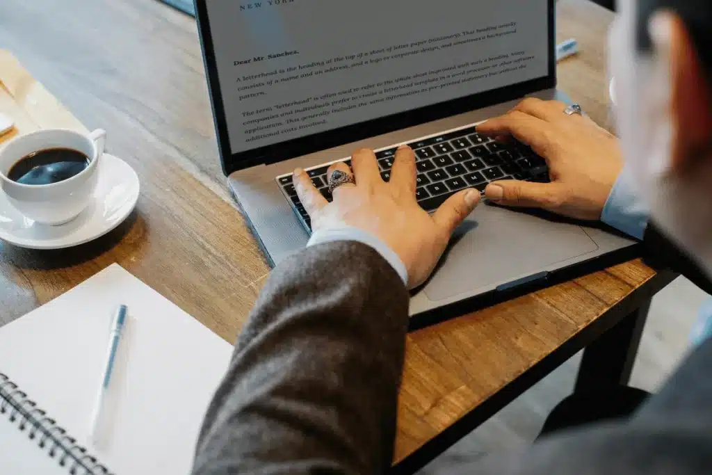 Close-up of hands typing a formal letter on a laptop in an office setting.