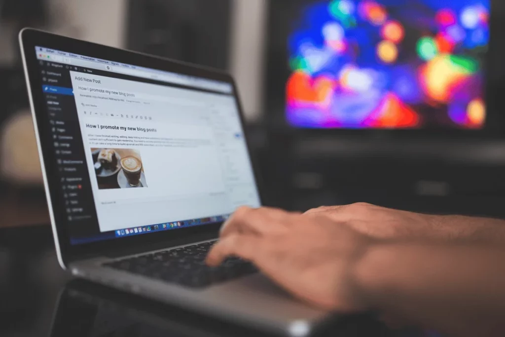 Blogging on a MacBook with an artistic blur of lights in the background for ambiance.