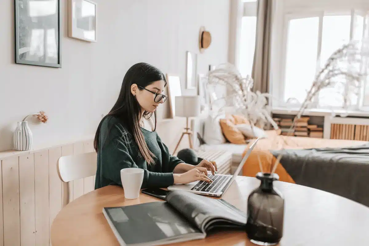 Indoor work setting with woman at laptop and coffee cup.