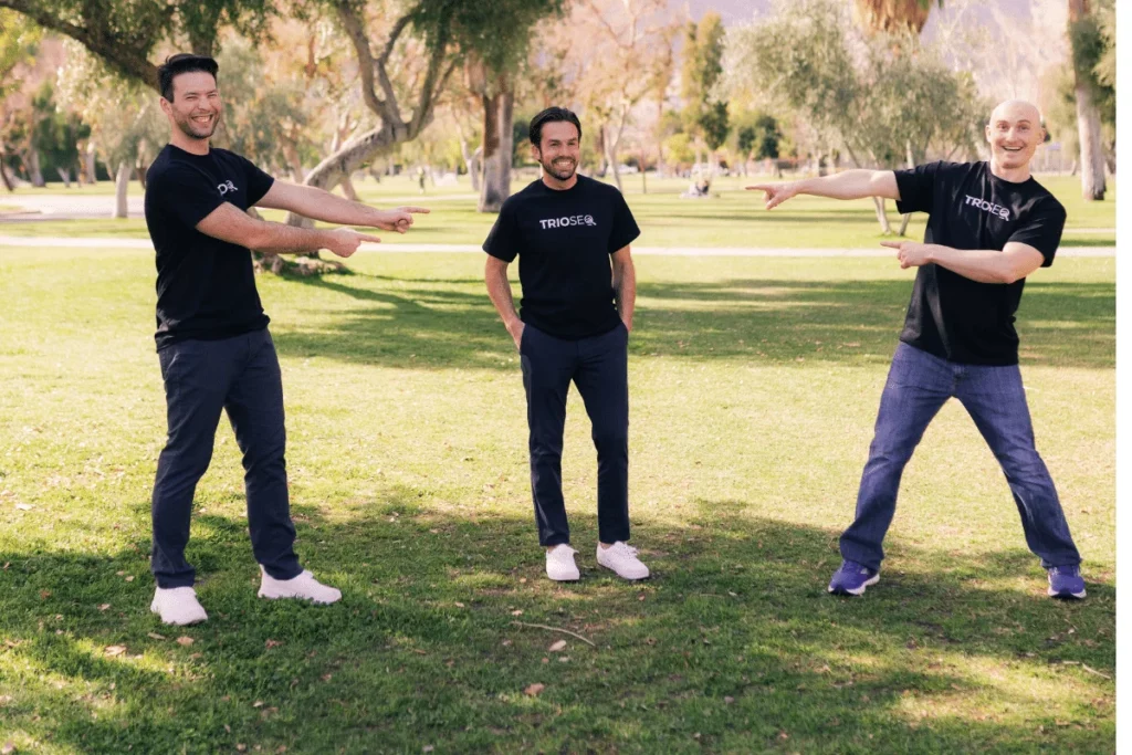Smiling trio Steven, Connor, and Nathan model black TRIOS&reg; t-shirts outside.