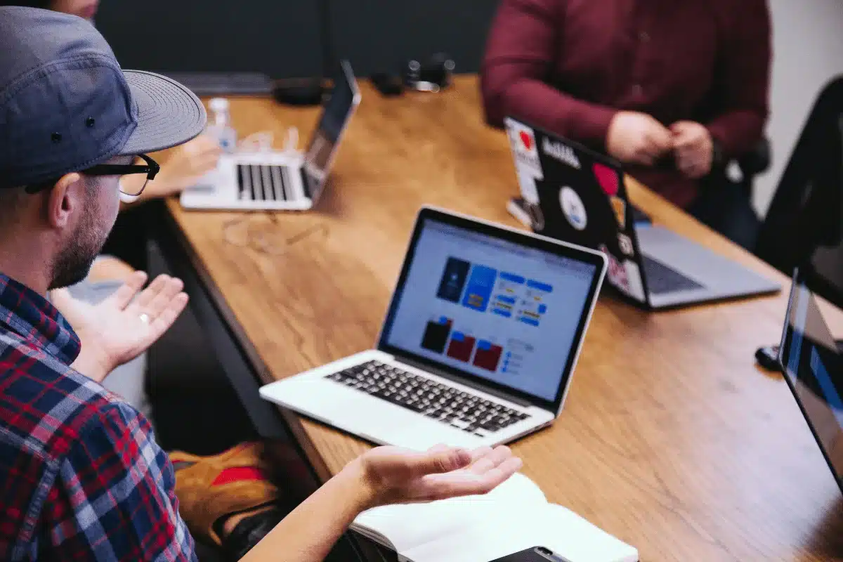 Group of professionals in a meeting, collaborating on a project using laptops.