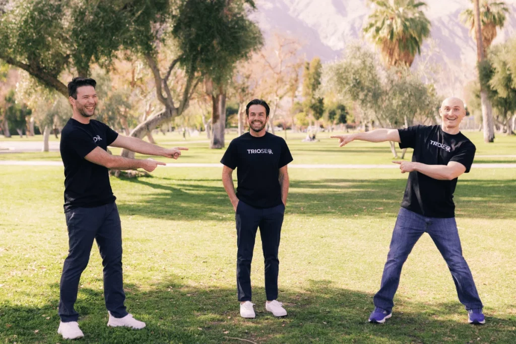 Smiling trio Steven, Connor, and Nathan model black TRIOS&reg; t-shirts outside.