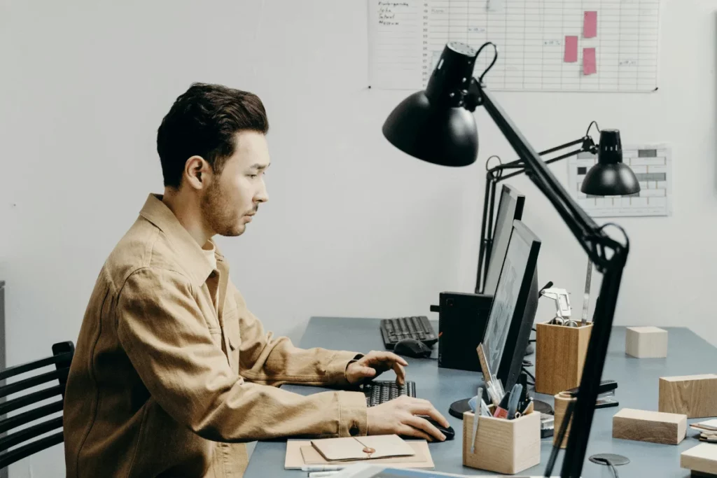 Young professional typing on a keyboard in a modern office with planning boards.