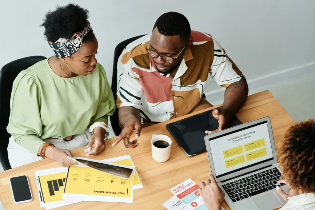 Team collaborating on social media marketing strategies with laptops and documents.