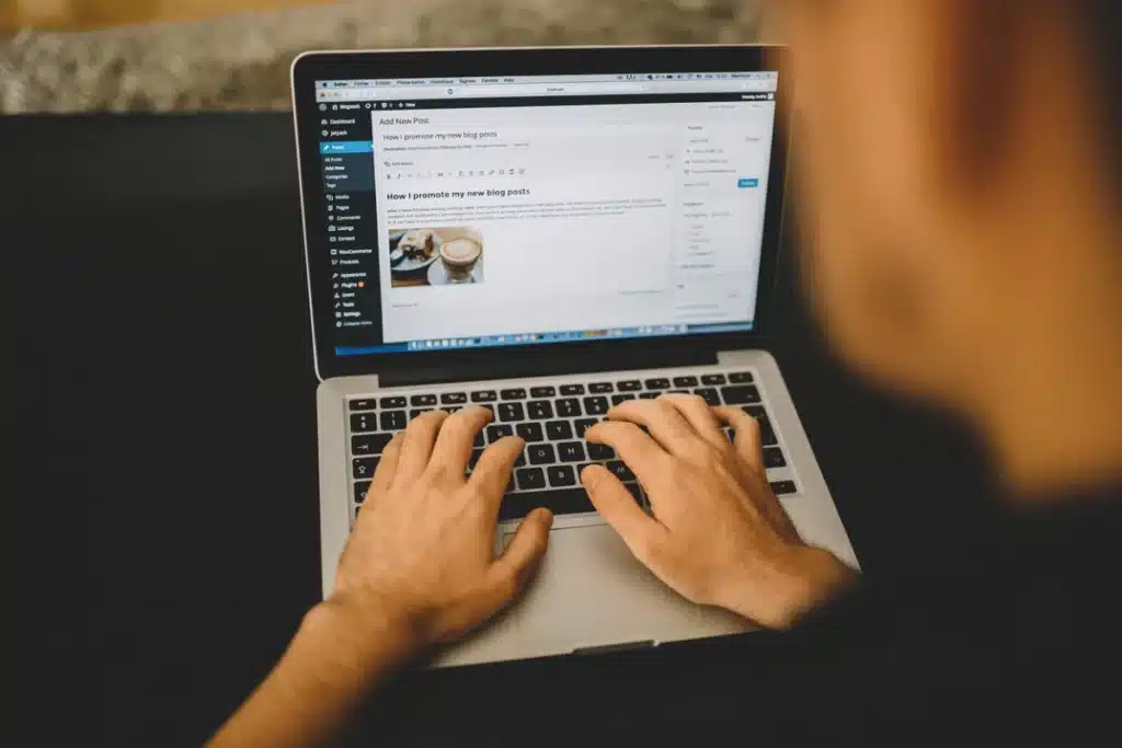 A person types on a laptop, editing a blog post titled "How I promote my new blog posts" on a WordPress dashboard.